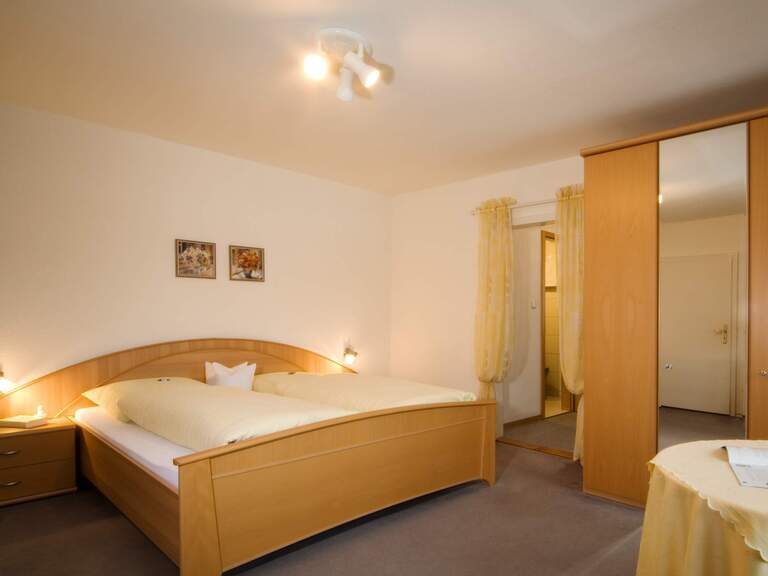 Schlafzimmer in einer Ferienwohnung von Riedl Reisen mit Holzbett und ländlicher Einrichtung