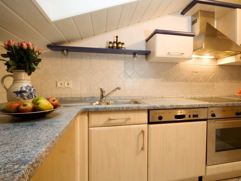 Ferienwohnungsküche mit Herd, Spüle und Schränken aus Holz in einer Unterkunft in Haidmühle